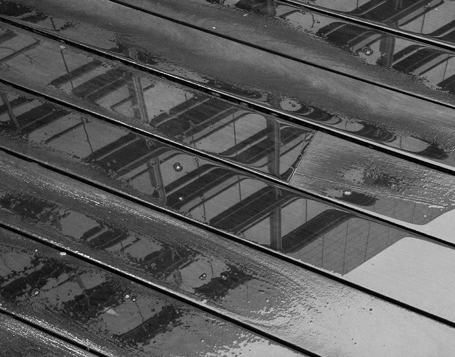 Black and White Photo of Building Reflected in Wet Decking.